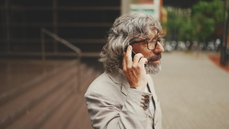 Mature businessman with beard and glasses wearing gray jacket walks up the stairs leaving the...