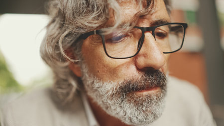 Clouse up, mature businessman with beard in eyeglasses,wearing gray jacket working using laptop pc...