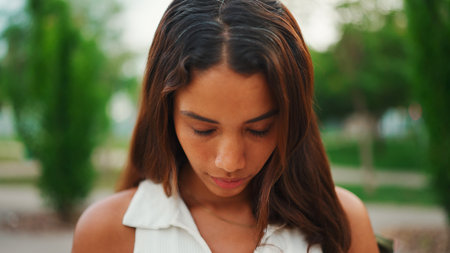 Clouse-up, beautiful girl with brown long hair, tanned skin wearing white top raises her headの写真素材