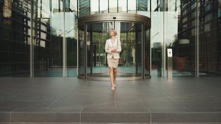 Businesswoman with blond hair wearing beige suit leaving business centerの写真素材