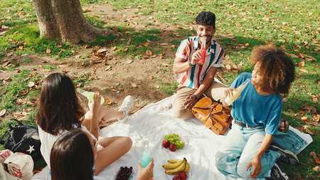Happy smiling young multinational people at picnic on summer day outdoors. Friends have fun weekend together, relaxing in the park at picnicの写真素材