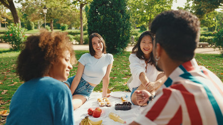 Happy smiling young multinational people at picnic on summer day outdoors. Friends have fun weekend together, relaxing in the park at picnicの写真素材
