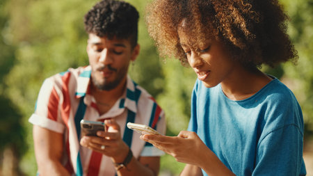 Close-up of young man with curly hair wearing striped shirt sitting in park having picnic on summer...