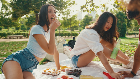 Happy smiling young multinational people at picnic on summer day outdoors. Friends have fun weekend together, relaxing in the park at picnicの写真素材