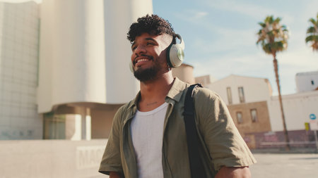 Young man with beard in an olive-colored shirt listens to music on headphones, dancesの写真素材