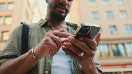 Young smiling man with beard dressed in an olive color shirt uses phone map app on the old city backgroundの写真素材