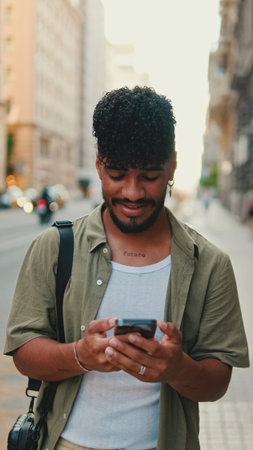 Young smiling man with beard dressed in an olive color shirt uses phone map app on the old city...