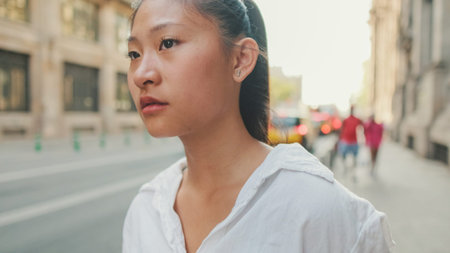 Closeup, Young woman using mobile phone while standing next to the road. Girl looks around