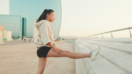Asian girl in sportswear does workout, stretching and gymnastics on modern buildings backgroundの写真素材