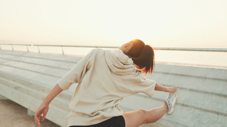 Asian girl in sportswear does workout, stretching and gymnastics on modern buildings background