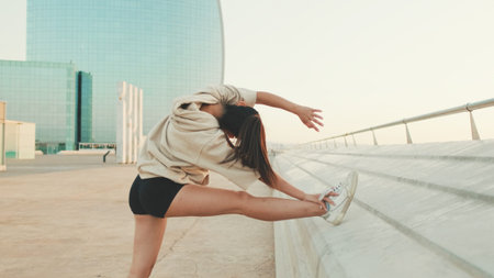 Asian girl in sportswear does workout, stretching and gymnastics on modern buildings background