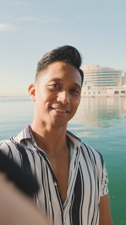 Close-up of young man standing on dock taking selfie with cell phone