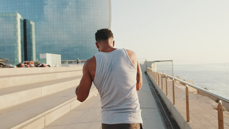 Close up, young bearded male athlete doing workout, stretching on the embankmentの写真素材
