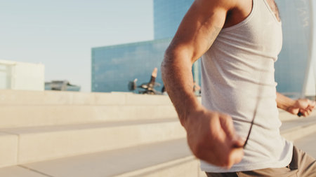 Young bearded male fit athlete jumping rope on the embankment