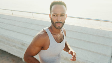 Young bearded male fit athlete runs along the promenade