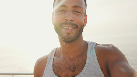 Close up, young bearded male fit athlete uses cell phone, takes selfie while resting after training...