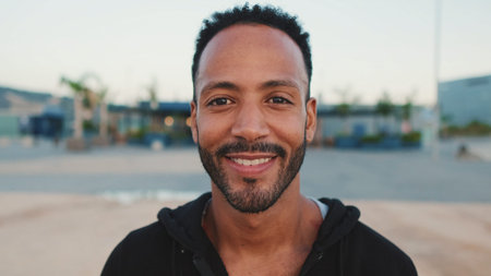 Close-up, young bearded male athlete standing on the embankment, looking at the sea. Guy turns his...