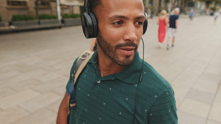 Young man tourist walks around the square of the old city, listens to music in headphones
