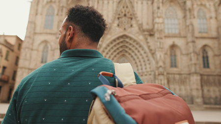 Close-up of young man tourist with backpack on his shoulder, looking at the sights while standing in...