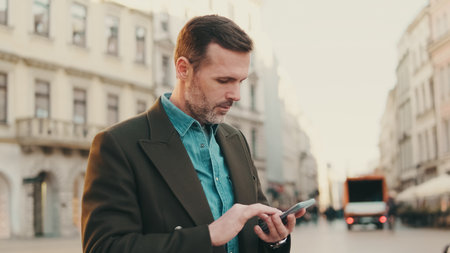 Middle aged man using map app on mobile phone on the old town backgroundの写真素材