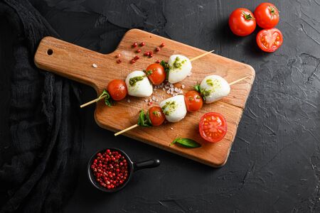 caprese salad skewer with tomato on sticks Italian traditional caprese salad ingredients. Mediterranean food. over black stone background overhead space for text.の写真素材