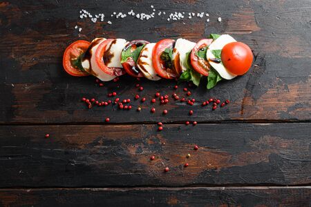 Top view of fresh italian caprese salad with tomatoes, mozzarella, green basil sliced on old kitchen table top view space for text.の写真素材