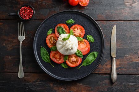 traditional italian burrata cheese Salad,olive oil, fork in plate old rustic wood planks background. Flat layの写真素材