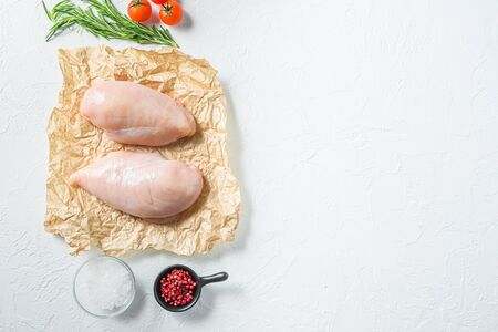 Raw meat, ready for grill or barbeque chicken breast filet, with herbs and spices on craft paper over white background, top view space for textの写真素材