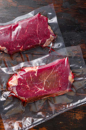 Rump beef steak in vacuum sealed bag on dark old wooden table, top viewの写真素材