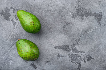 Organic avocado over grey textured background, top view with space for text