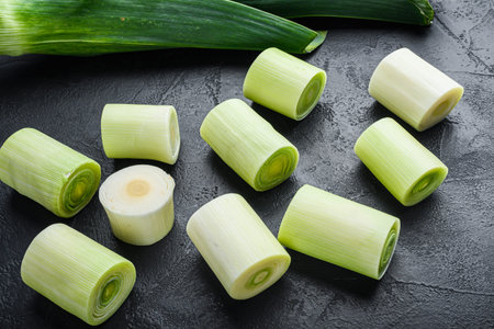 Green leeks sultan oninon uncooked with herbs ingredients , on textured black background side view