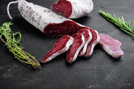 Longaniza, traditional salami spanish sausage on black textured surface.