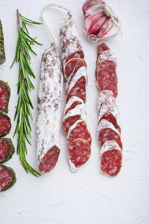 Variety of dry cured fuet and chorizosalami sausages, whole and sliced on white textured background.の写真素材