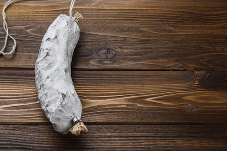 Salchichon sausage on light wooden background with copy space.