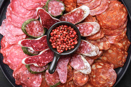 Spanish cold meat plate, chorizo, fuet, lomo,longaniza and salchichon on balck background, top viewの写真素材