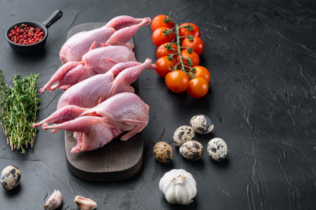 Fresh raw meat quail ready for cooking, on black textured background with space for textの写真素材
