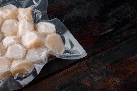 Scallops, in vacuum pack, on dark wooden background with copy spaceの写真素材