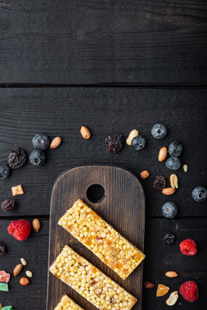Fruit berry, nut energy bars. Healthy snack, top view with copy space, on black wooden tableの写真素材