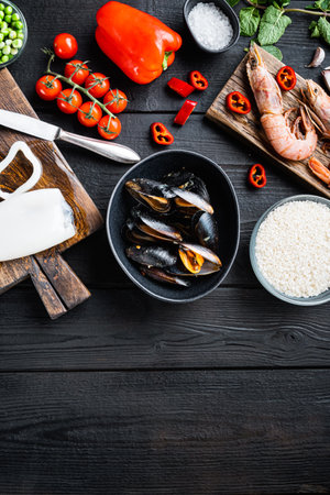 Seafood for spanish paella with vegetable and spices on black wooden background, flat lay with copy space, food photo.の写真素材