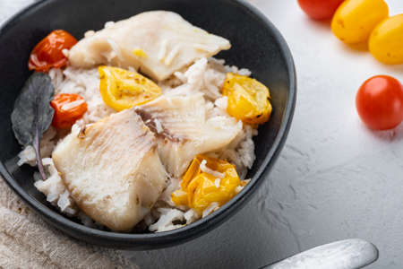 Tilapia fish with basmati rice and cherry tomatoes, in bowl, on white backgroundの写真素材
