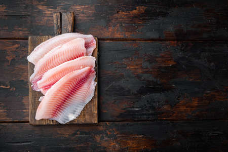 Raw tilapia fish fillet meat cuts, on old wooden table, top view with copy space for textの写真素材