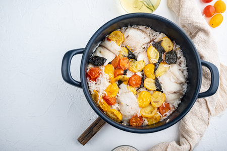 One pan fabulous fish, with basmati rice and cherry tomatoes, on white background, top view with...