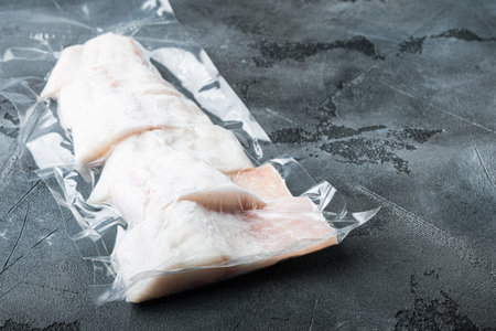 Raw haddock fish skinless plastic vacuum packaged, on gray background with copy space for text