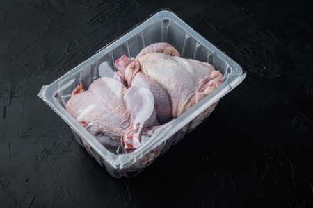 Raw chicken in plastic sealed plastic box, on black background with copy space for textの写真素材