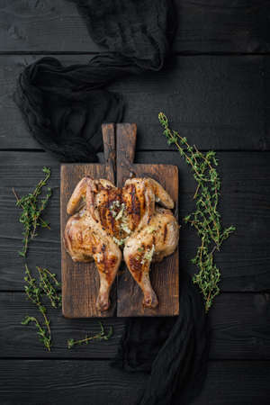 Roasted whole poussins, on black wooden background, top viewの写真素材