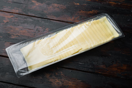 Cheddar cheese in vacuum pack, on dark wooden background