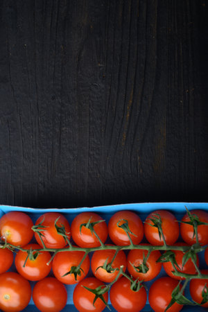 Red small cherry tomatoes, on black wooden table with copy space for textの写真素材