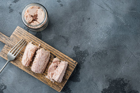 Canned tuna fillet meat in olive oil, on gray background, top view with copy space for textの写真素材