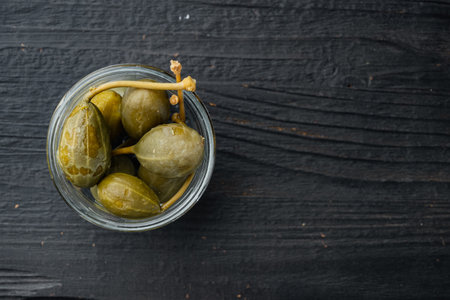 Organic pickled, canned capers, on black wooden background, top view with copy space for textの写真素材