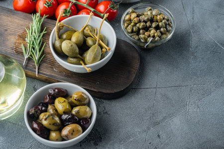 Mediterranean olives and capers with herbs, on gray background with copy space for textの写真素材